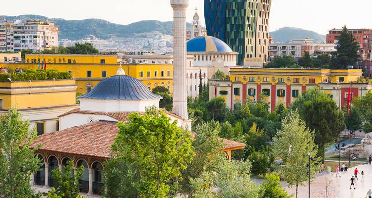 Edificios coloridos, mezquita con cúpula y torre moderna dominan el vibrante paisaje urbano de Tirana.