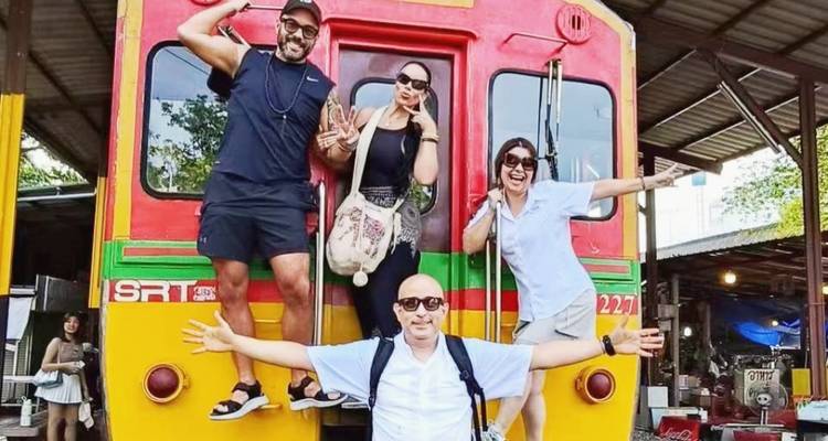 A group of people posing on the front of a colorful train.