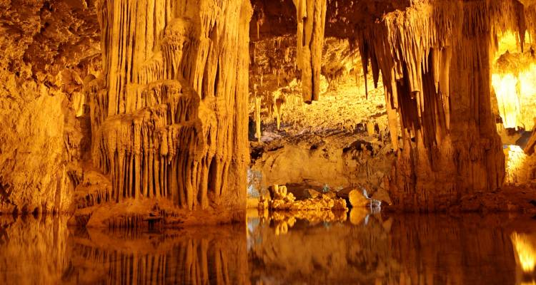 Grotte de stalactites éclairée par des lumières chaudes.