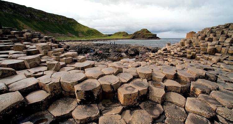 A landscape of interlocking basalt columns by the sea, a natural rock formation under a cloudy sky.