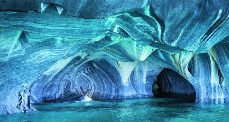 Lebhaft gefärbte Marmor-Höhlen mit blauem Wasser.