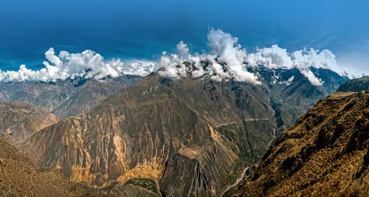 Panoramablick auf eine schroffe Berglandschaft mit Wolken.