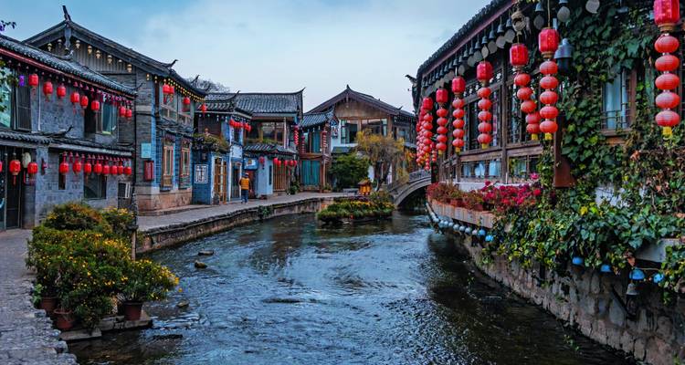 Calle tradicional china con faroles rojos y un pequeño canal.