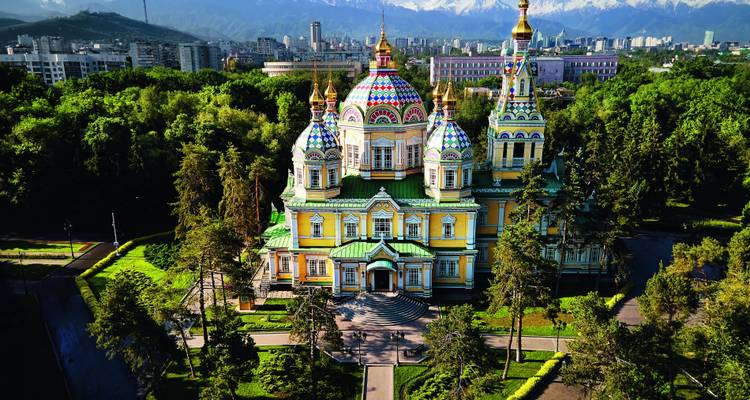 Kleurrijke Zenkov-kathedraal in Almaty omringd door bomen.