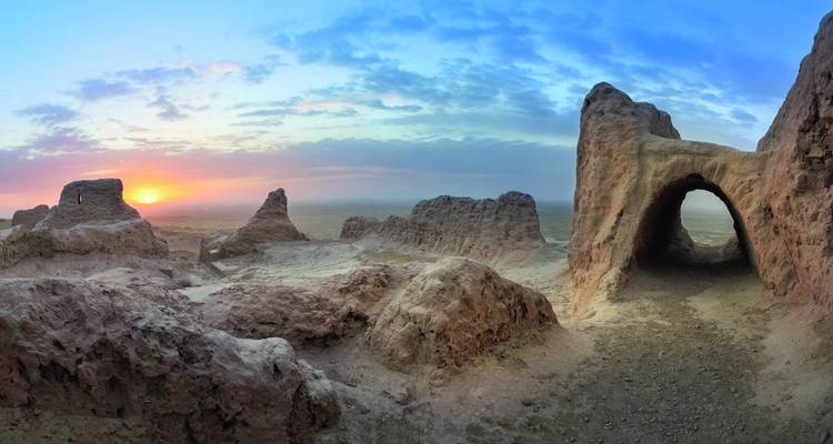 Oude fortificatieruïnes met een boogvormige ingang tijdens zonsondergang.