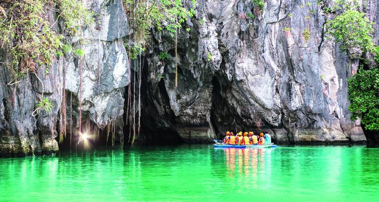 Gruppe von Menschen auf einer Bootstour in der Nähe eines Höhleneingangs in Puerto Princesa.