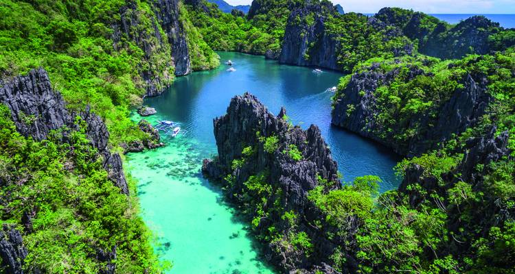 Luftaufnahme einer abgeschiedenen Bucht mit türkisfarbenem Wasser und Kalksteinklippen in El Nido.