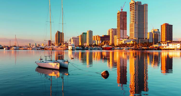 Moderne Skyline von Manila mit sich in ruhigem Wasser spiegelnden Gebäuden.