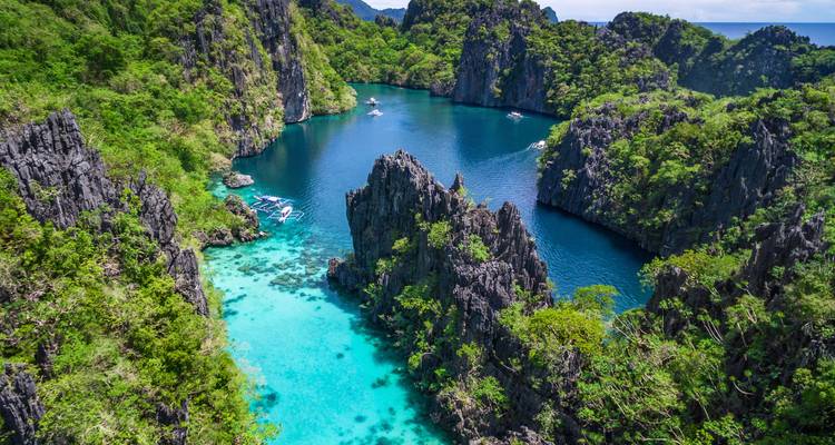 Vista aérea de acantilados de piedra caliza dentados que resguardan una laguna de color azul cristalino en El Nido.