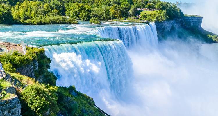 Krachtige waterval van Niagara Falls met turkoois water dat over een rotsachtige klif stort, omringd door weelderig groen.