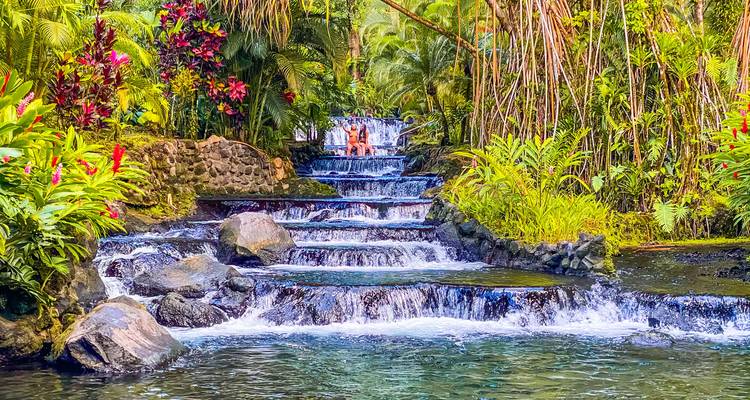 Cascade tropicale et bassin avec des gens qui se baignent.