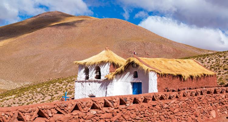 Un petit bâtiment traditionnel au toit de chaume dans un paysage désertique.