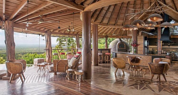 Open-air restaurant with wooden furnishings and scenic view.