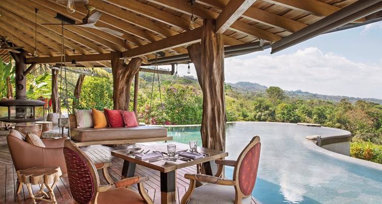 Infinity pool decked with chairs overlooking a valley.