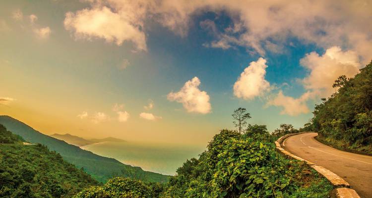 A winding road along a mountainous landscape at sunset.