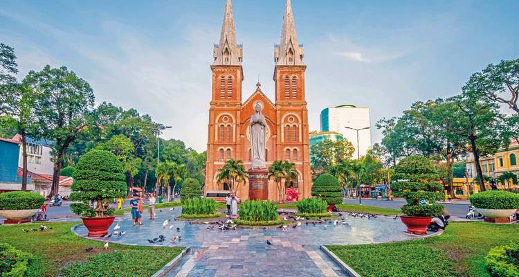 A historical building with twin spires and people in a plaza.