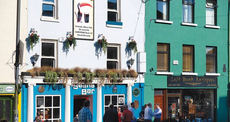 Pub animé et boutique d'antiquités sur une rue avec des gens dehors.