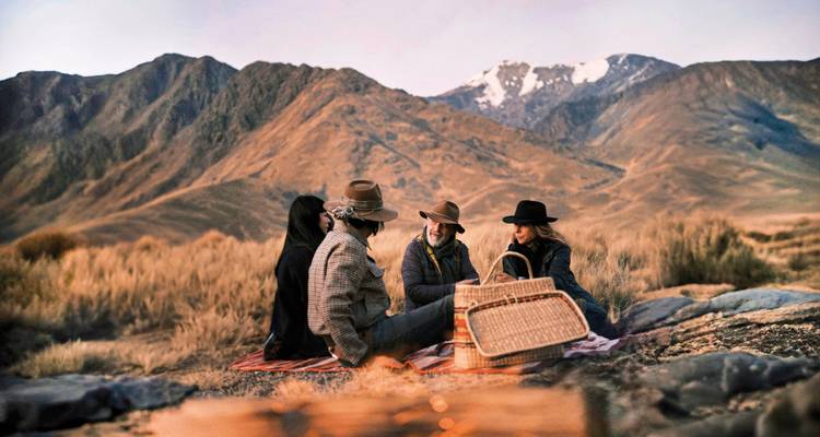 Un groupe de personnes faisant un pique-nique avec des montagnes en arrière-plan.