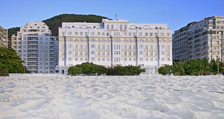 A beachfront hotel with a sandy beach in front.
