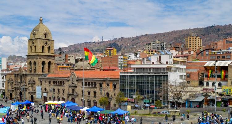 Place de la ville avec des gens et un bâtiment historique avec un drapeau bolivien.