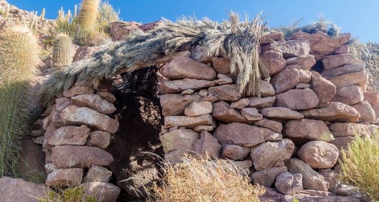 Structure en pierre avec un toit de chaume dans un paysage rocheux.