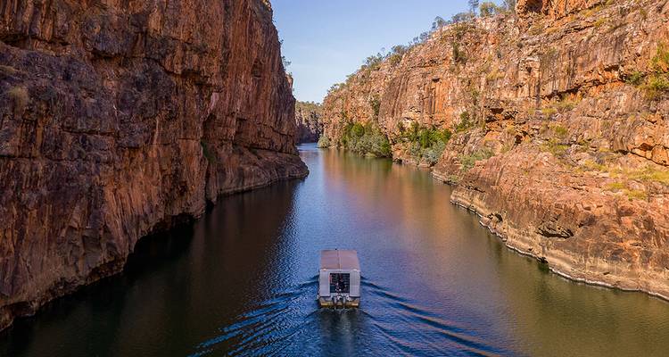 A riverboat navigating a narrow waterway between towering rock cliffs.