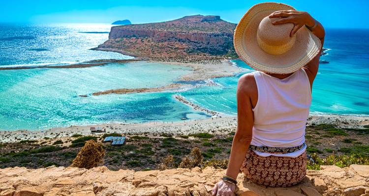 Person sitting overlooking a lagoon with clear blue waters.