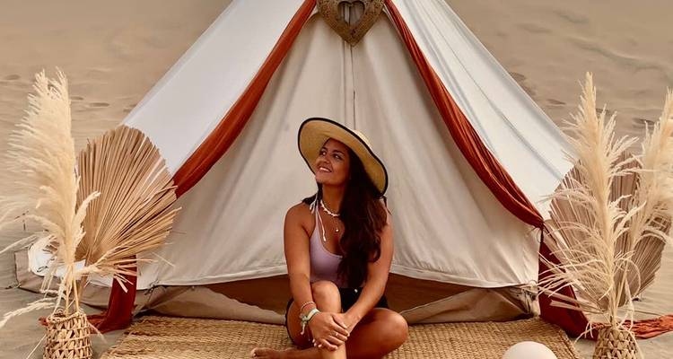 Woman sitting in front of a decorative tent in the desert.