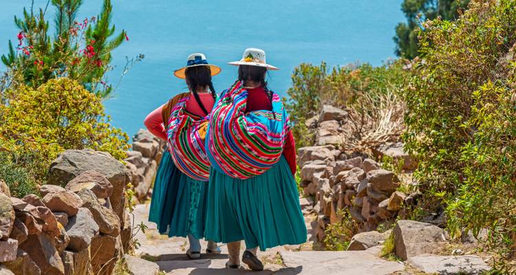 Two women in traditional clothing walking along a scenic path.