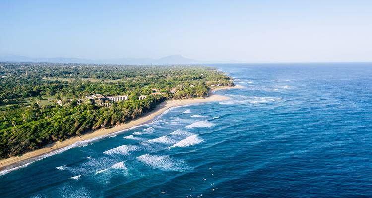 Vue aérienne d'une station balnéaire côtière avec des vagues qui se brisent sur la plage.