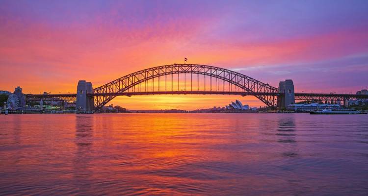 Sonnenuntergang über dem Wasser mit Sydneys Harbour Bridge.