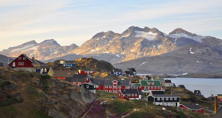 Maisons colorées sur une colline avec des montagnes et de l'eau.