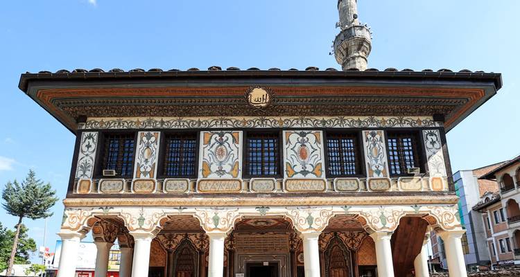 Fachada pintada de forma intrincada de la histórica Mezquita Sarena con su esbelt minaret contra el cielo azul