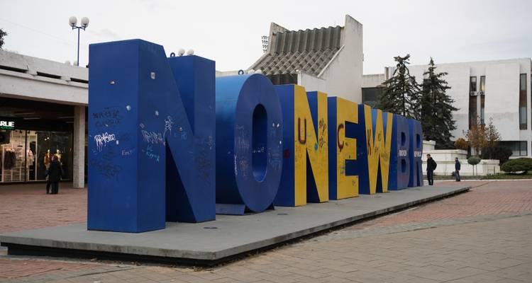 Grand monument bleu et jaune « NEWBORN » sur une place publique à Pristina.