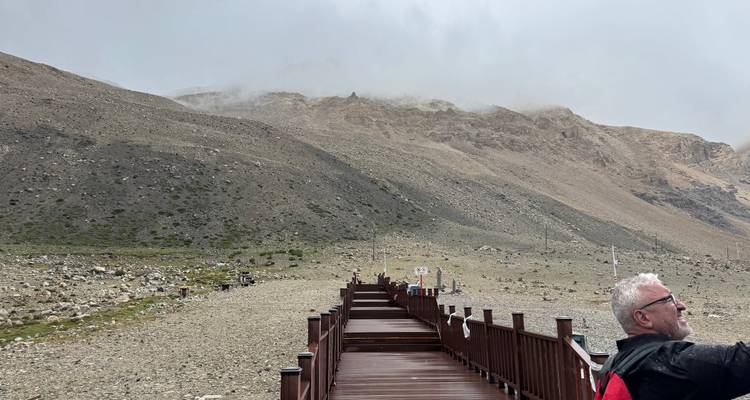 Un sendero montañoso brumoso con una pasarela de madera.