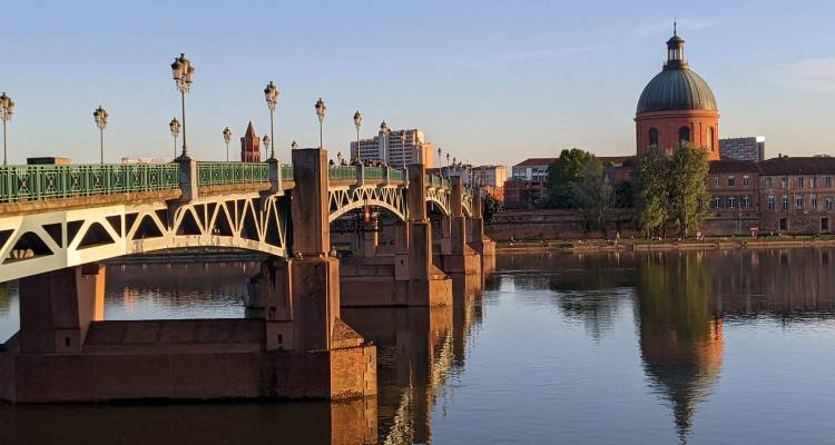 Pont en pierre historique sur la Garonne avec le dôme de La Grave à Toulouse au lever du soleil.