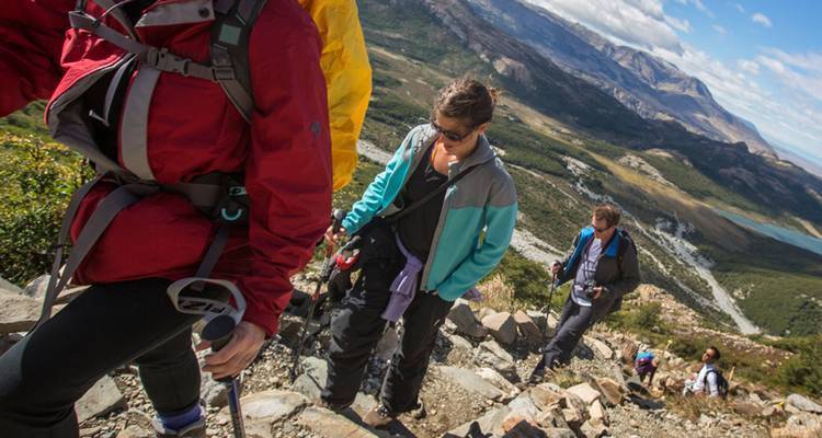 Wandelaars beklimmen een rotsachtig bergpad met panoramische uitzichten op Patagonië.