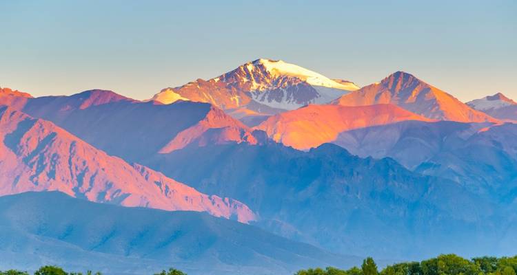 Majestueuse chaîne de montagnes avec une lueur rosâtre au lever ou au coucher du soleil.