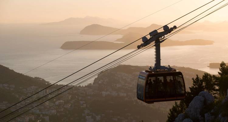 Cable car against a sunset sailing over the Dubrovnik landscape.