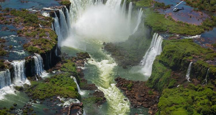 Vista aérea de una cascada poderosa con vegetación exuberante a ambos lados.