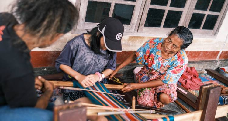 Dos mujeres y un niño participando en tejido tradicional.