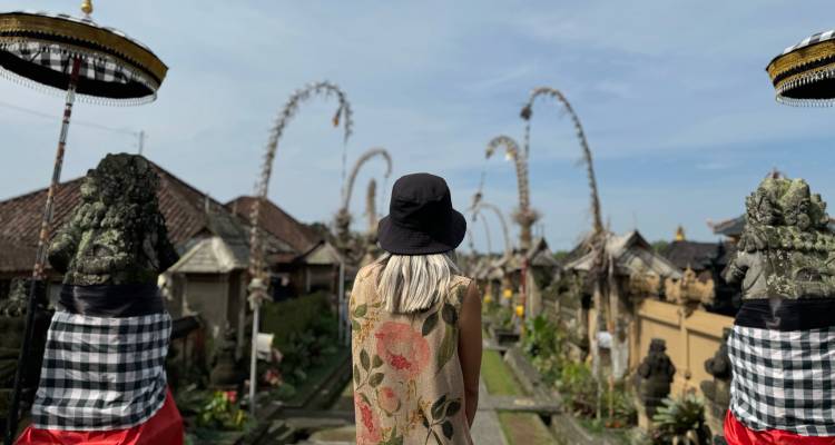 Une personne avec un chapeau se tenant dans un temple balinais traditionnel orné de décorations ornementales.
