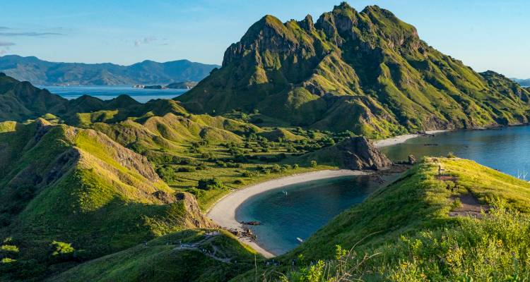 Vue à couper le souffle d'une plage avec des collines verdoyantes et des eaux bleues cristallines.