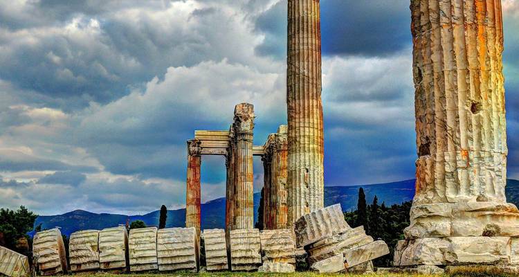 Ruines de colonnes antiques sous un ciel dramatique.