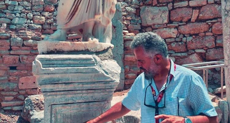 Hombre examinando una estatua antigua y ruinas.