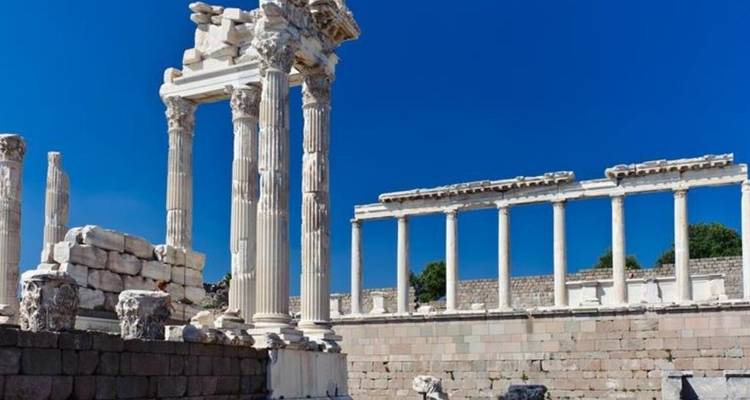 Ruinas de ciudad antigua con columnas y escalones bajo un cielo azul despejado.