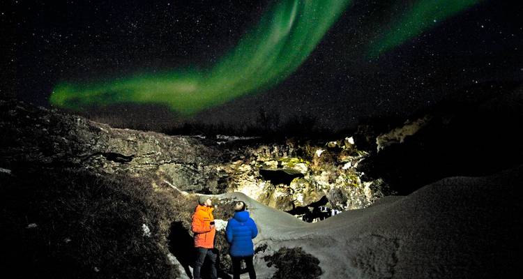 Aurores boréales illuminant le ciel au-dessus d'un paysage enneigé.