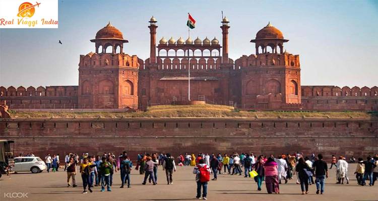 Historic red fort with a crowd of people in front.