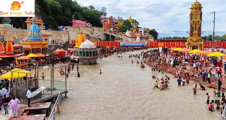 Crowded riverbank with temples and people bathing.