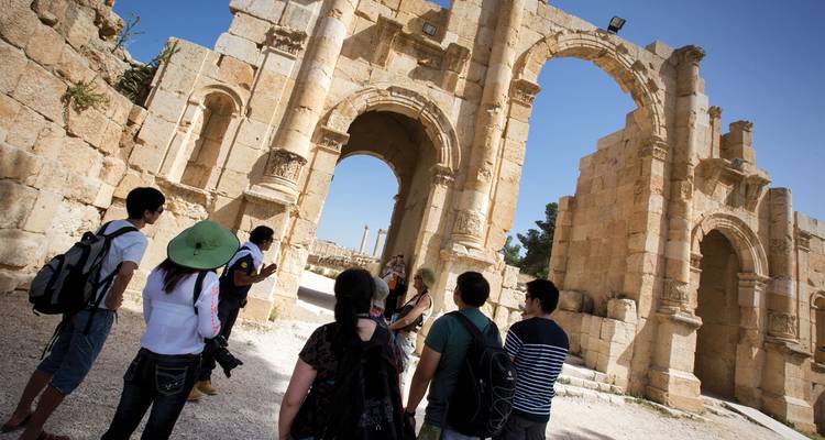 Los visitantes se reúnen debajo del antiguo arco triunfal en las ruinas romanas de Jerash.